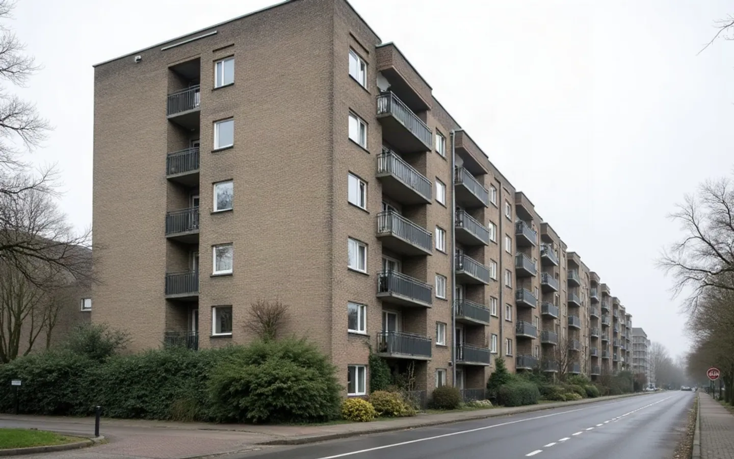 Naoorlogse appartementen met uitstekende balkons, van onderaf gefotografeerd tegen een bewolkte lucht.