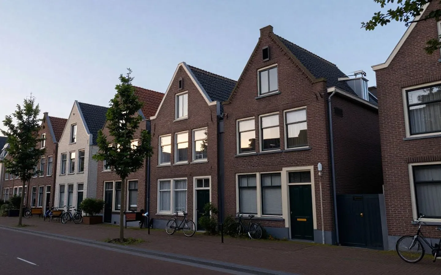 Een straat met eengezinswoningen achter volgroeide bomen.