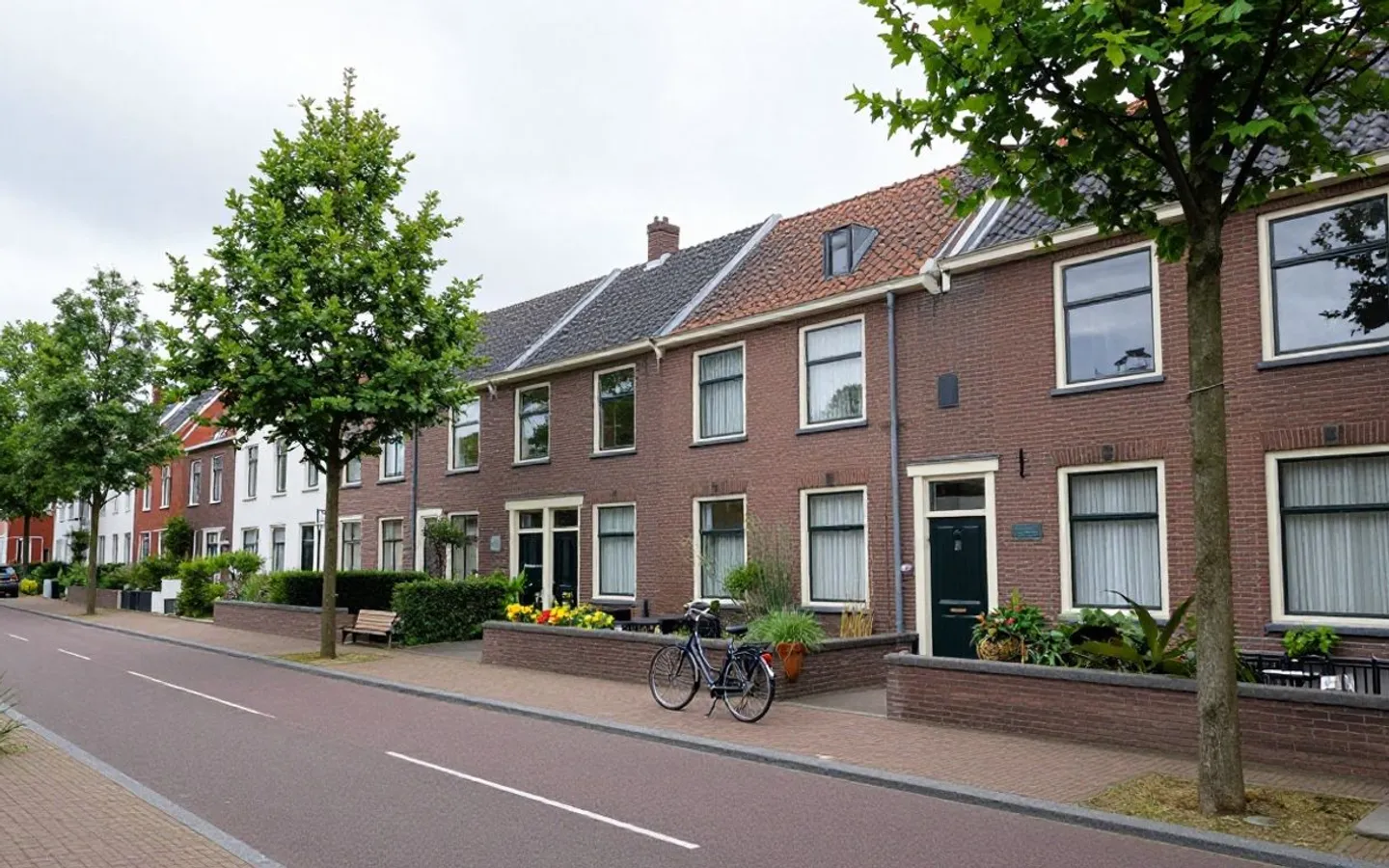 Rij Nederlandse rijwoningen aan een straat met geparkeerde fietsen